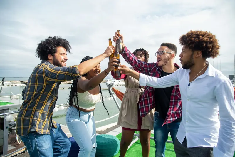 A group of friends raising beer bottles in a toast on the deck of a boat