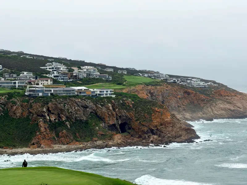 A coastal golf course on cliffs above the sea, with houses along the ridge