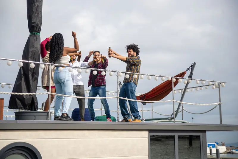 Friends on the deck of a boat under string lights, taking photos with their phones