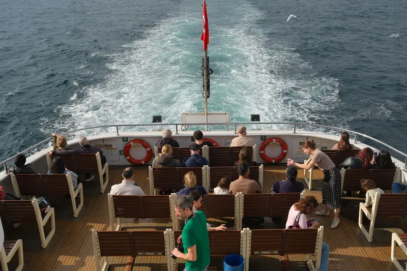 Pasajeros en la cubierta abierta de un barco de tour compartido en un día soleado en el mar