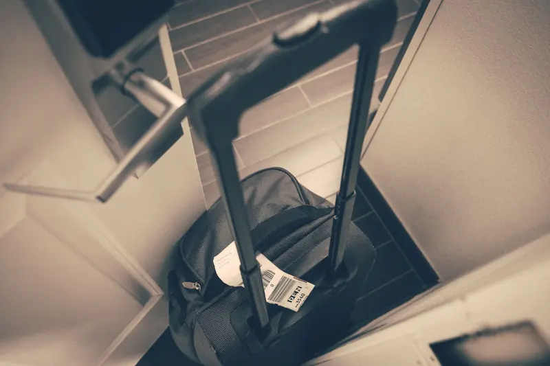 Rolling suitcase with a luggage tag standing by a hotel room door, seen from above