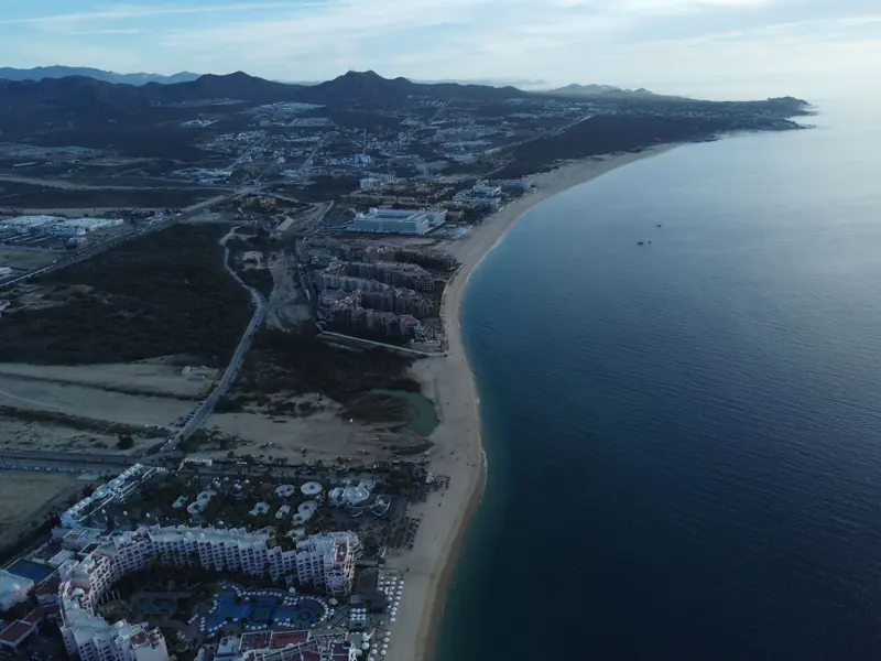 Aerial view of beachfront resorts and a long sandy shore on the Cabo San Lucas coast