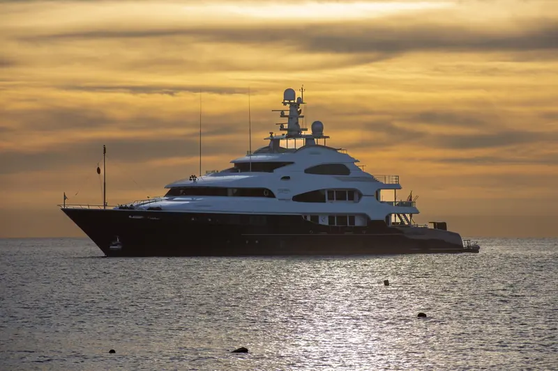 A motor yacht on calm water at sunset off Cabo San Lucas