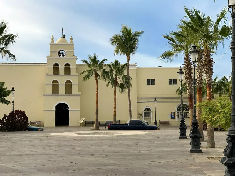 Mission church of Todos Santos, Baja California Sur, with its white bell tower and palm trees