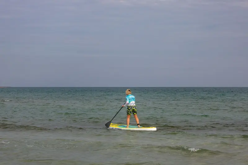 A person paddle boarding on calm sea under a clear sky