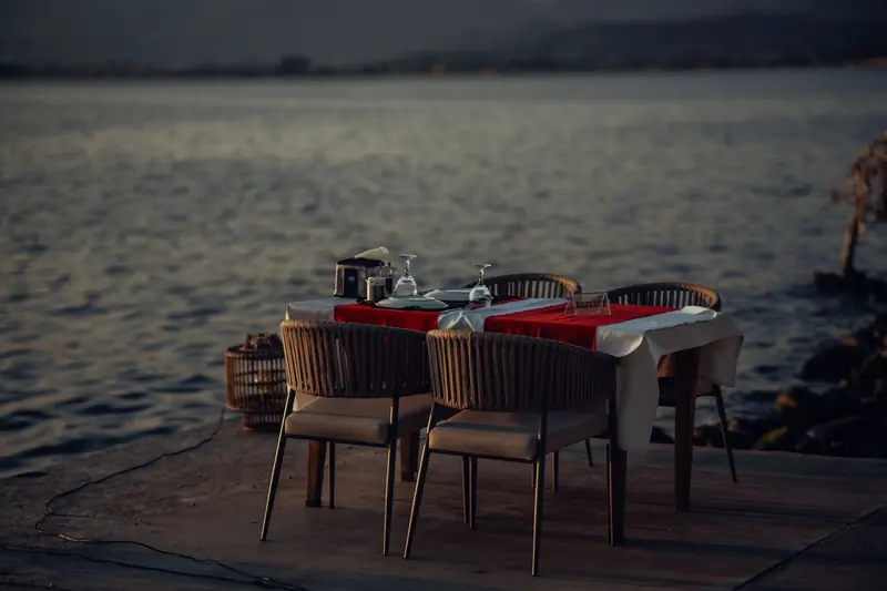 A table for two set on a pier over calm water at dusk