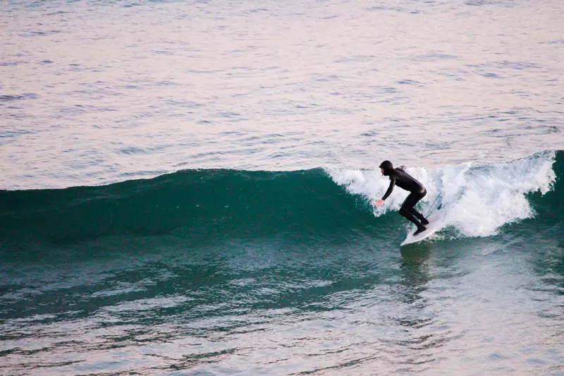 A surfer riding a green wave as it breaks into white foam