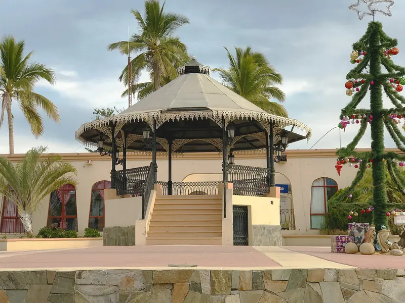 Quiosco de la plaza de Todos Santos con palmeras y un árbol de Navidad decorado al lado