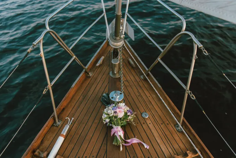 A bridal bouquet lying on the teak deck of a yacht with the sea beyond