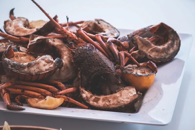 Grilled spiny lobster halves with lemon on a white plate