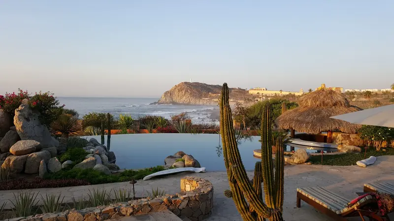 Alberca infinita con cactus y plantas del desierto sobre el mar en un resort al amanecer