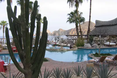 Pool and beach palapas of the hotel in 2006, then Meliá Cabo San Lucas, with Land's End behind