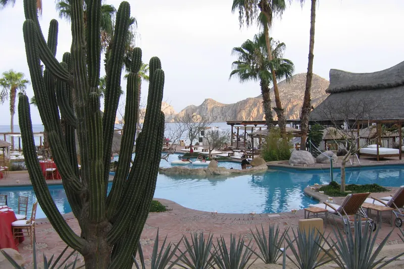 Pool and beach palapas of the hotel in 2006, then Meliá Cabo San Lucas, with Land's End behind