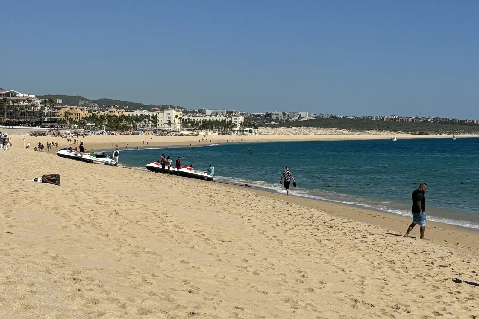 Playa El Médano frente a los hoteles RIU, con motos acuáticas en la arena y hoteles en la orilla