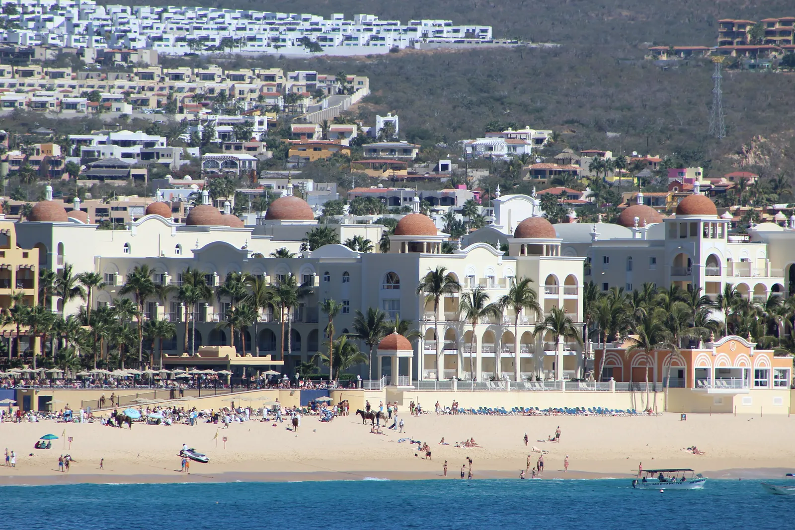 Riu Palace Cabo San Lucas seen from the sand of El Médano, with the beach busy in front of it