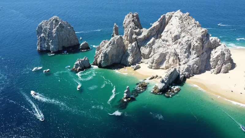 Playa del Amor y las rocas de Finisterra desde el aire, con lanchas en el agua clara