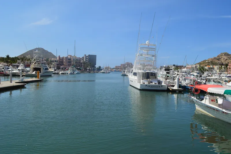 Calm water and moored yachts at Marina Cabo San Lucas on a clear morning, with hotels and the hills behind