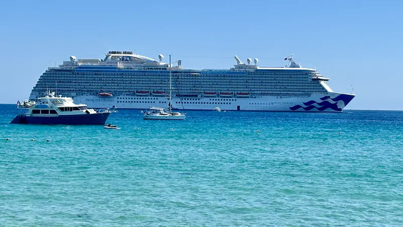 Un crucero anclado frente a la playa Médano con una lancha en el agua turquesa