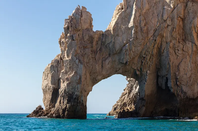 The Arch at Land's End in warm late afternoon light, seen from the water