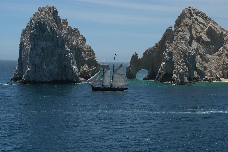 Un velero de mástiles altos pasando frente al Arco en Finisterra