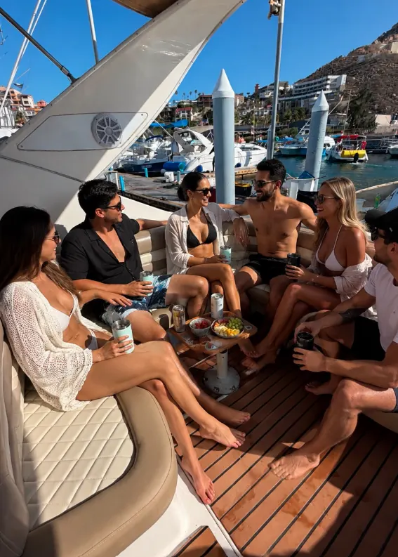 Grupo de amigos con bebidas en la cubierta del Bayliner 33 en la marina
