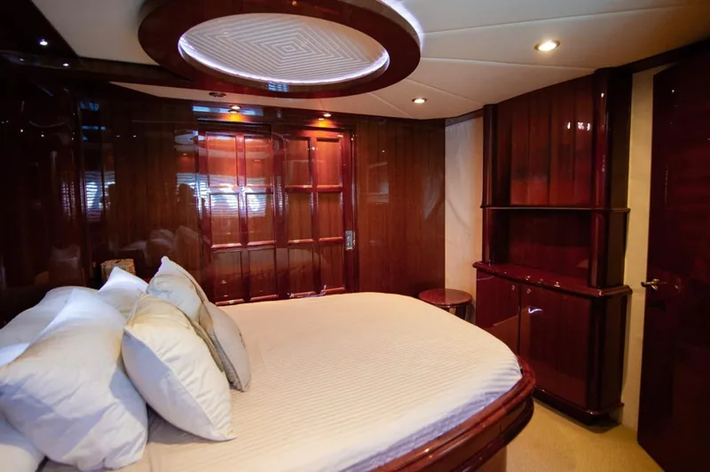 Camarote principal del McKinna 70 con cama grande, ropa de cama blanca y paneles de madera