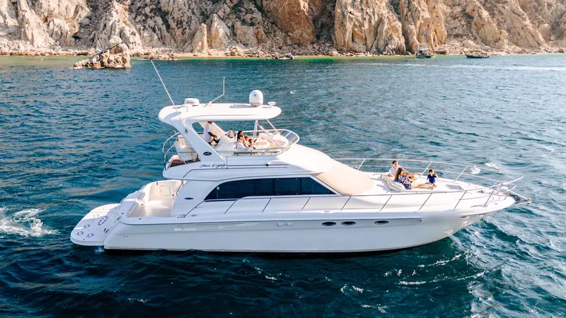カボのランズエンドの崖の横を進むフライブリッジヨットSea Ray 55の船首でくつろぐゲスト