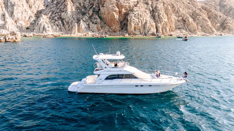 The Sea Ray 55 underway in blue water below the granite cliffs of Land's End