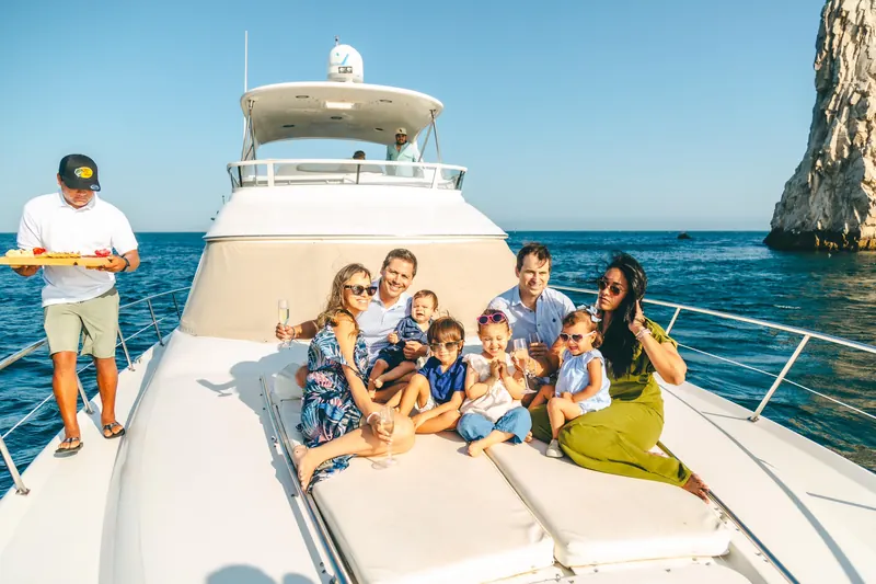 Family with children on the bow of the Sea Ray 55 with the Arch of Cabo San Lucas behind