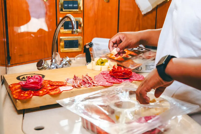 Tripulante cortando una tabla de carnes frías en la cocina del Sea Ray 55
