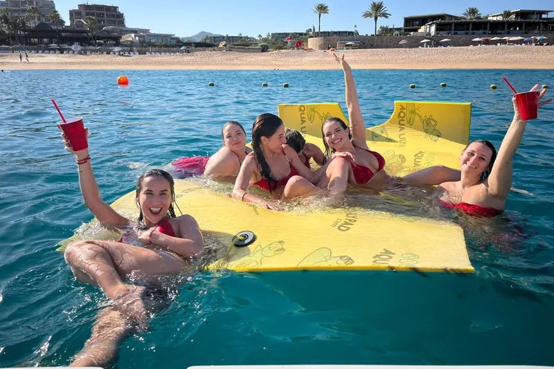 Seis amigas con traje de baño rojo en el tapete flotante del Sea Ray 55 frente a la playa El Médano
