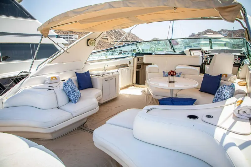 Salón con aire acondicionado del Sea Ray 65, con asientos blancos y una mesa