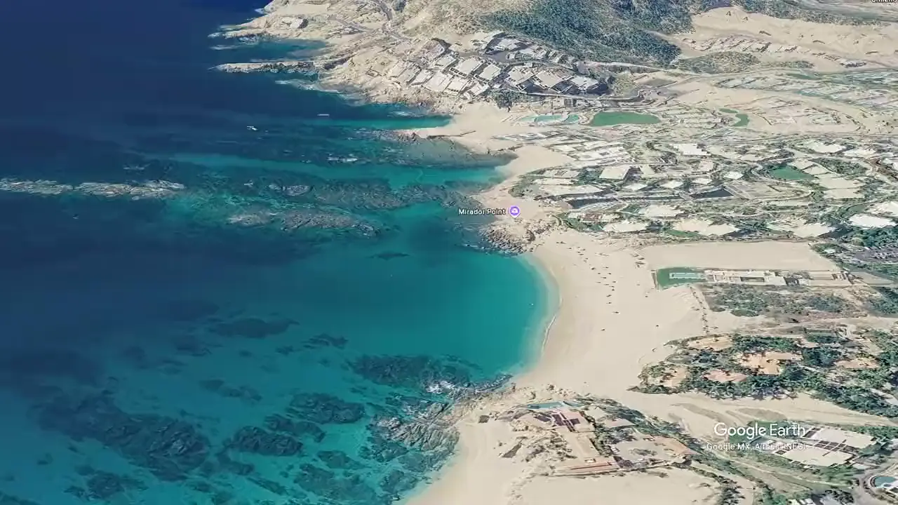 Aerial view of Chileno Bay with reef visible in the clear water and the beach curving along the shore